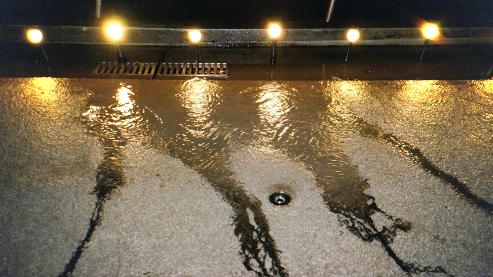 13 shots, one film. Shot 1: the rain and the bulbs, rain falls steadily, one bulb flickers and holds, nothing else moves, camera static shot, subtle, slow motion, steady camera
