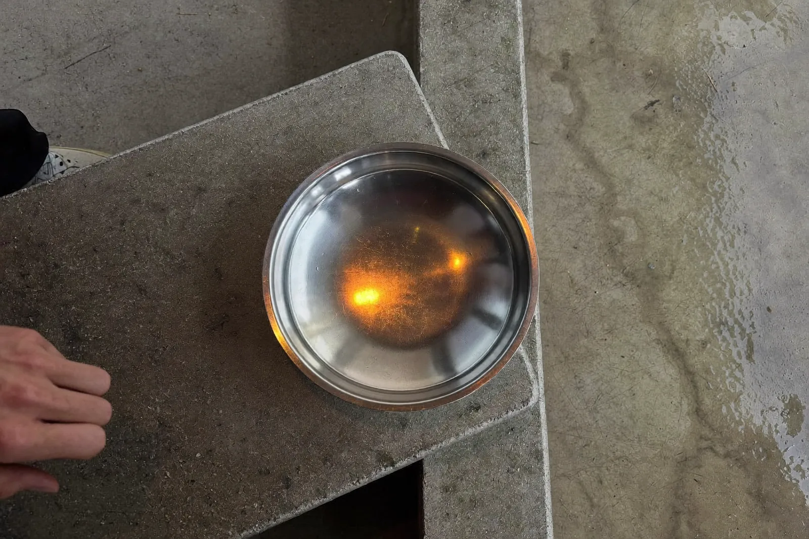 a steel developing tray on a wet concrete bench, amber safelight raking across the surface, quiet mood
