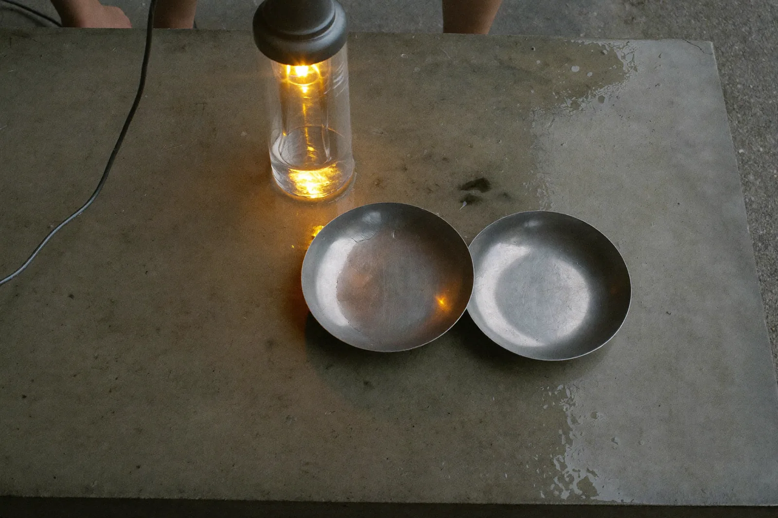 a steel developing tray on a wet concrete bench, amber safelight raking across the surface, quiet mood