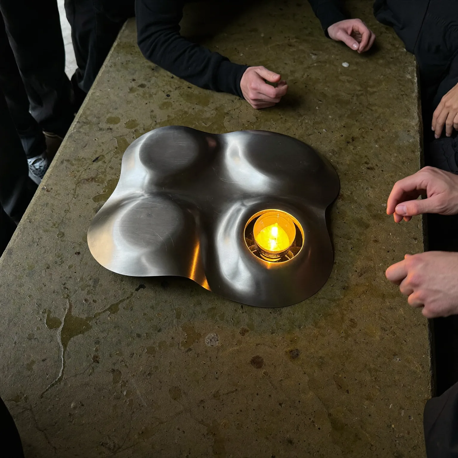 a steel developing tray on a wet concrete bench, amber safelight raking across the surface, quiet mood