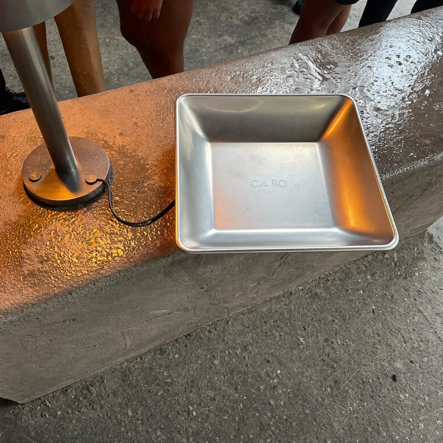 a steel developing tray on a wet concrete bench, amber safelight raking across the surface, quiet mood