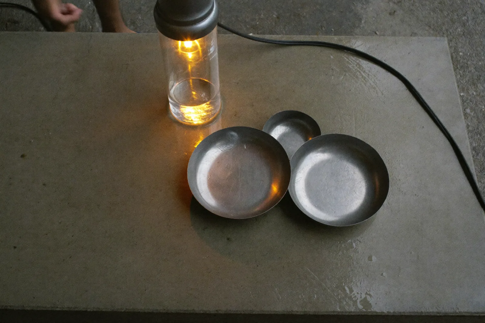 a steel developing tray on a wet concrete bench, amber safelight raking across the surface, quiet mood