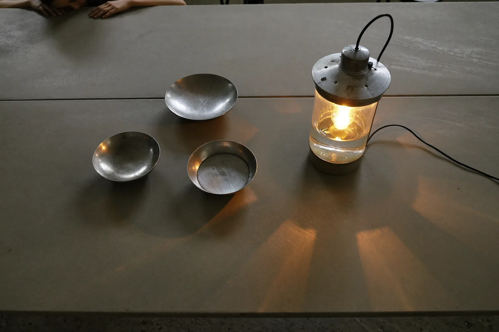 a steel developing tray on a wet concrete bench, amber safelight raking across the surface, quiet mood